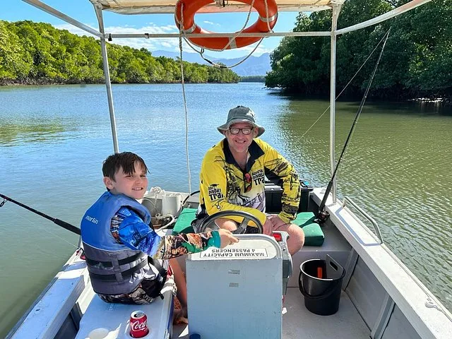 A man and a boy sitting on a boat in Trinity Inlet