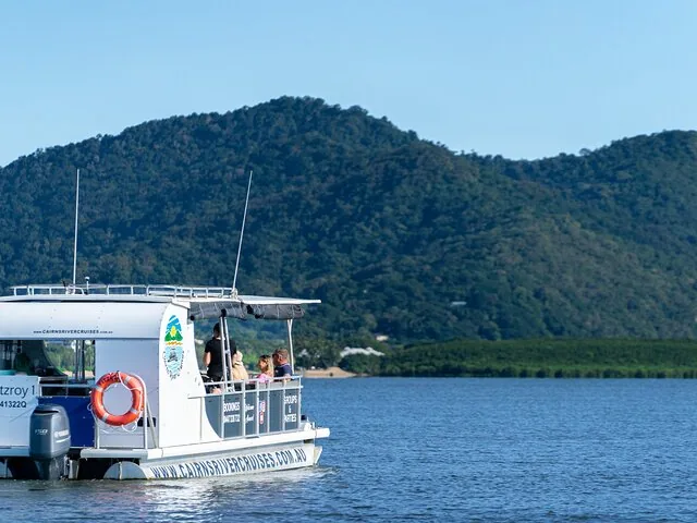 Ausflugsboot auf dem Wasser, im Hintergrund sattgrüne Hügel.